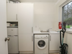 A compact kitchen with a washing machine, a sink, and a window with a view. - Carnmhor (Aberdeen)