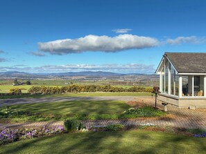 A house with a conservatory, a well-maintained lawn, and a view of distant hills. - Carnmhor (Aberdeen)