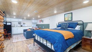 Ein Schlafzimmer mit Bett, Nachttisch, Kommode, Stuhl, Sofa, Küchenzeile und Badezimmer.