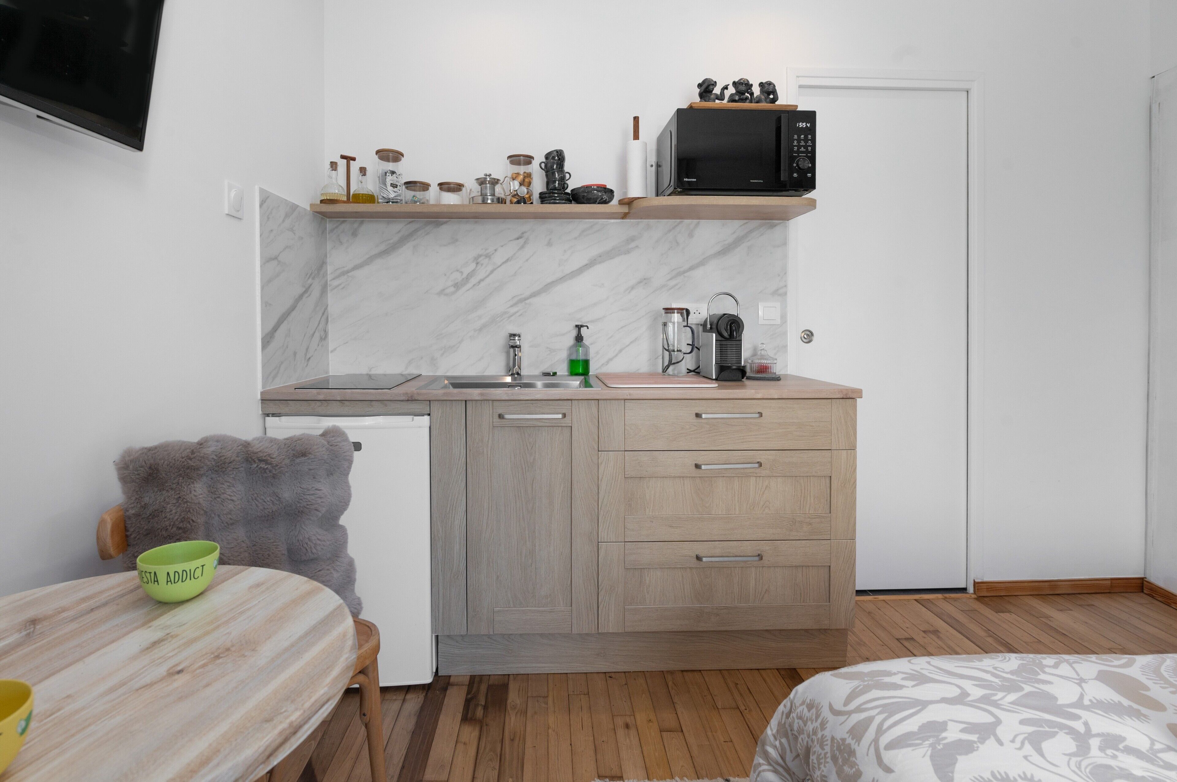 Una cocina compacta con microondas, pileta y muebles de madera.