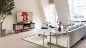 Ein modernes Wohnzimmer mit einer Couch, einem Couchtisch, einem Fernseher und einem großen Fenster.