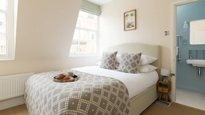 Un dormitorio con cama, mesita de noche, ventana y puerta.