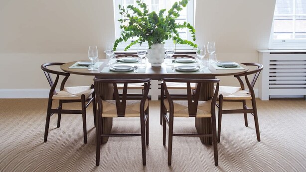Una mesa de comedor con seis sillas, una planta en maceta y un ventanal con persianas.