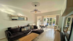 A modern living room with a sofa, coffee table, and a dining area with a table and chairs. - Comfortable house in a quiet location close to the beach (Puget-sur-Argens)