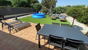 An outdoor patio with a dining table, chairs, lounge chairs, and a blue inflatable pool. - Comfortable house in a quiet location close to the beach (Puget-sur-Argens)