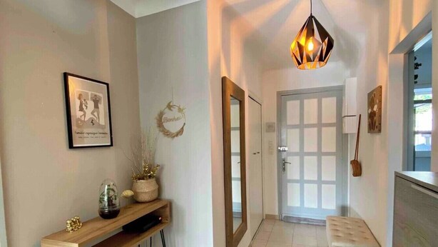 A hallway with a wooden console table, a mirror, a bench, and a pendant light. - Comfortable house in a quiet location close to the beach (Puget-sur-Argens)