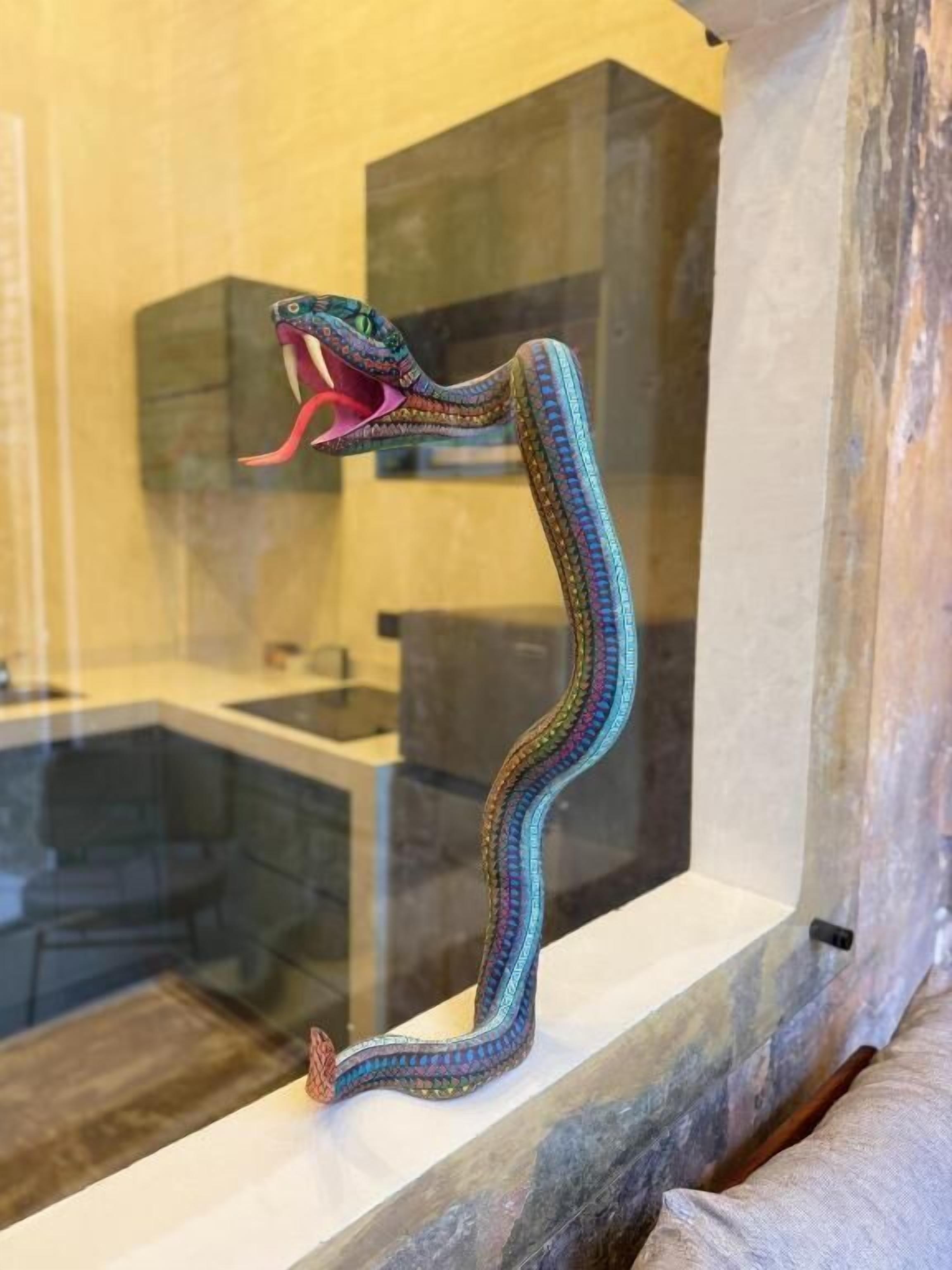 Una escultura de serpiente en un baño con recinto de vidrio.