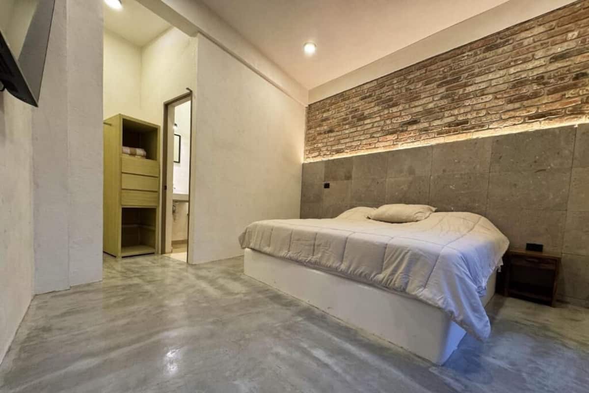 Una camera da letto con un letto, un armadio in legno e una parete decorata con mattoni.