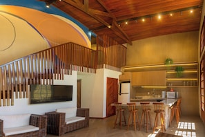 A modern kitchen with a built-in microwave, bar stools, and a large island.