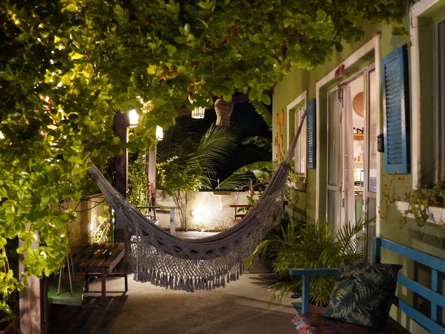 A hammock in a well-lit outdoor area with plants and a bench.