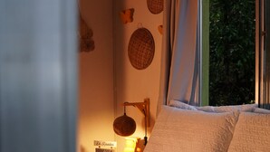 Ein Bett mit weißer Bettwäsche, eine Nachttischlampe und eine Wand mit gewebten Körben.