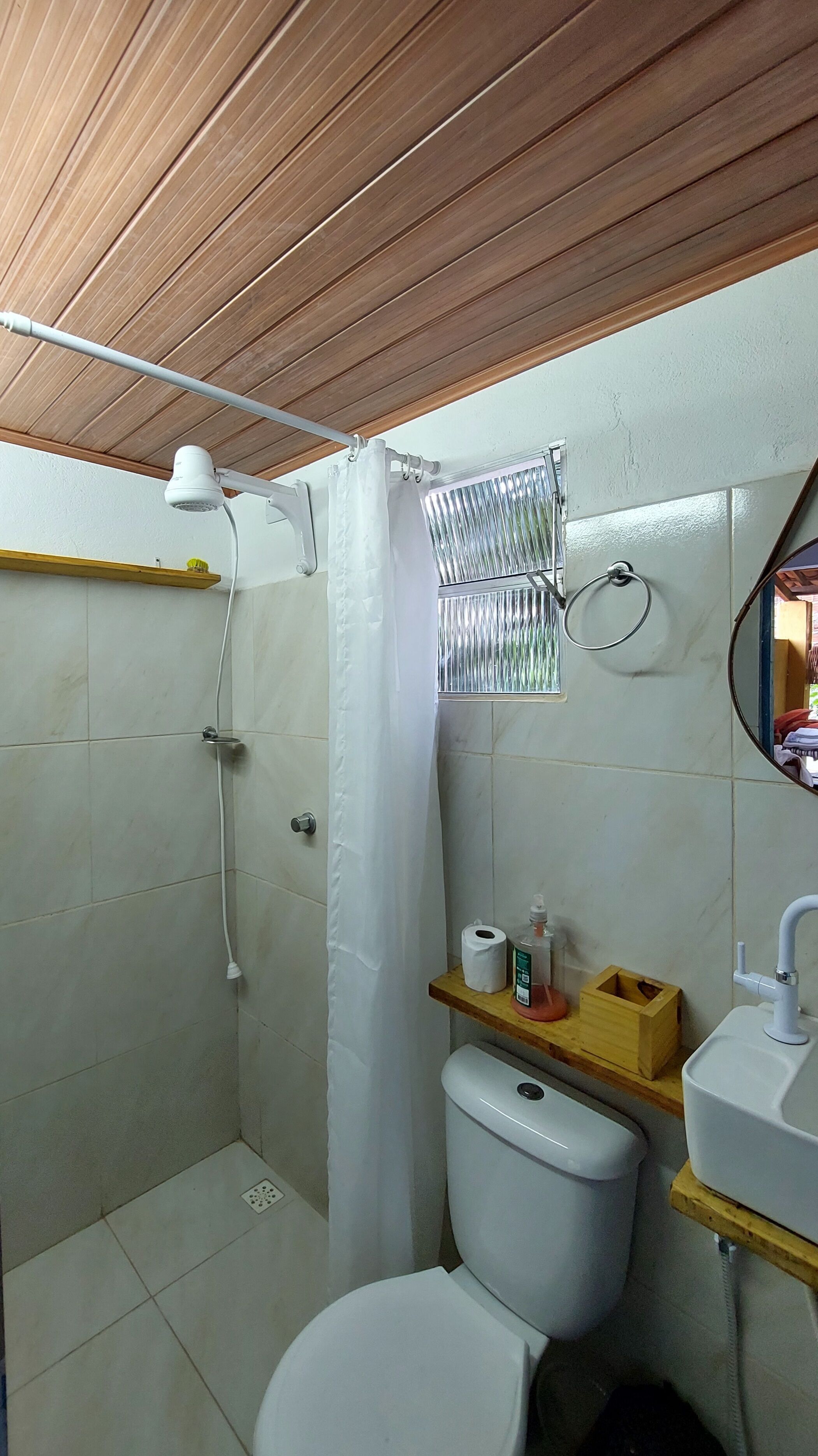 A bathroom with a shower, toilet, sink, and a mirror.