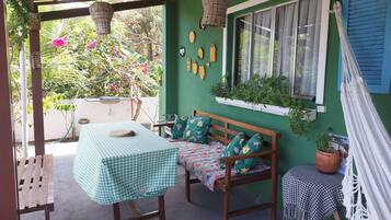A patio with a checkered table, wooden bench, and potted plants.
