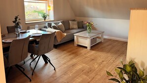 A cozy loft-style room with a dining area, a sofa, a coffee table, and a hanging light fixture. - To Huus modern apartment with country view near Verden (Verden (Aller))