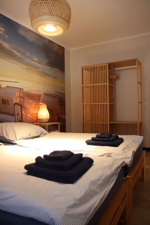 Ein Schlafzimmer mit einem Bett, einem Nachttisch mit Lampe, einem Holzschrank und Wandgemälde.