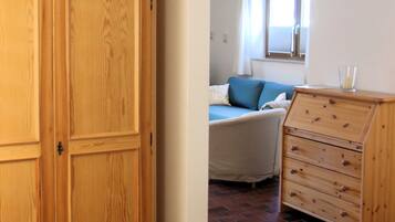 Una habitación con un armario grande de madera, una cama con cabecera azul y un aparador con cajones.