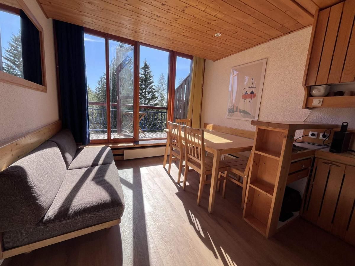 Une pièce de taille modeste comprenant un canapé, une table à manger, des chaises et un coin cuisine avec des meubles en bois.
