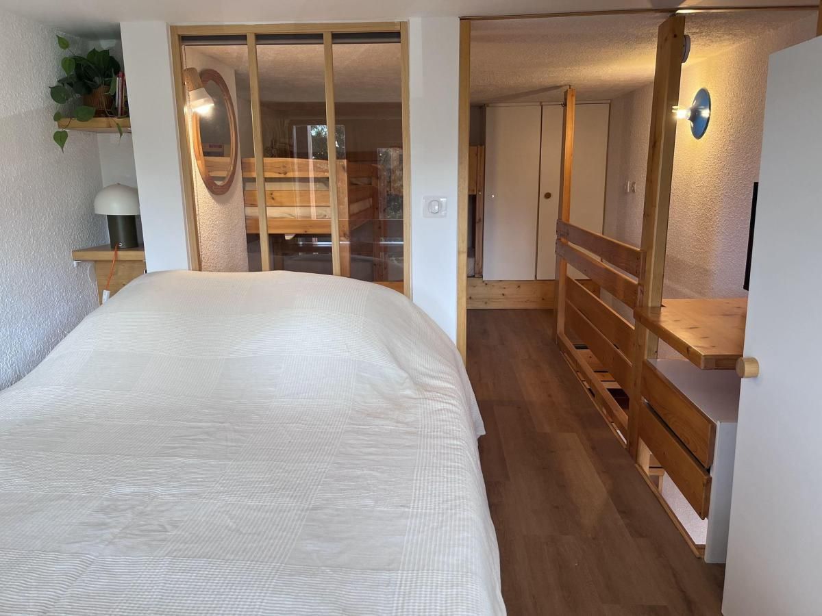 Una camera da letto con un letto grande, pavimento in legno, un armadio e una piccola scrivania con una lampada.