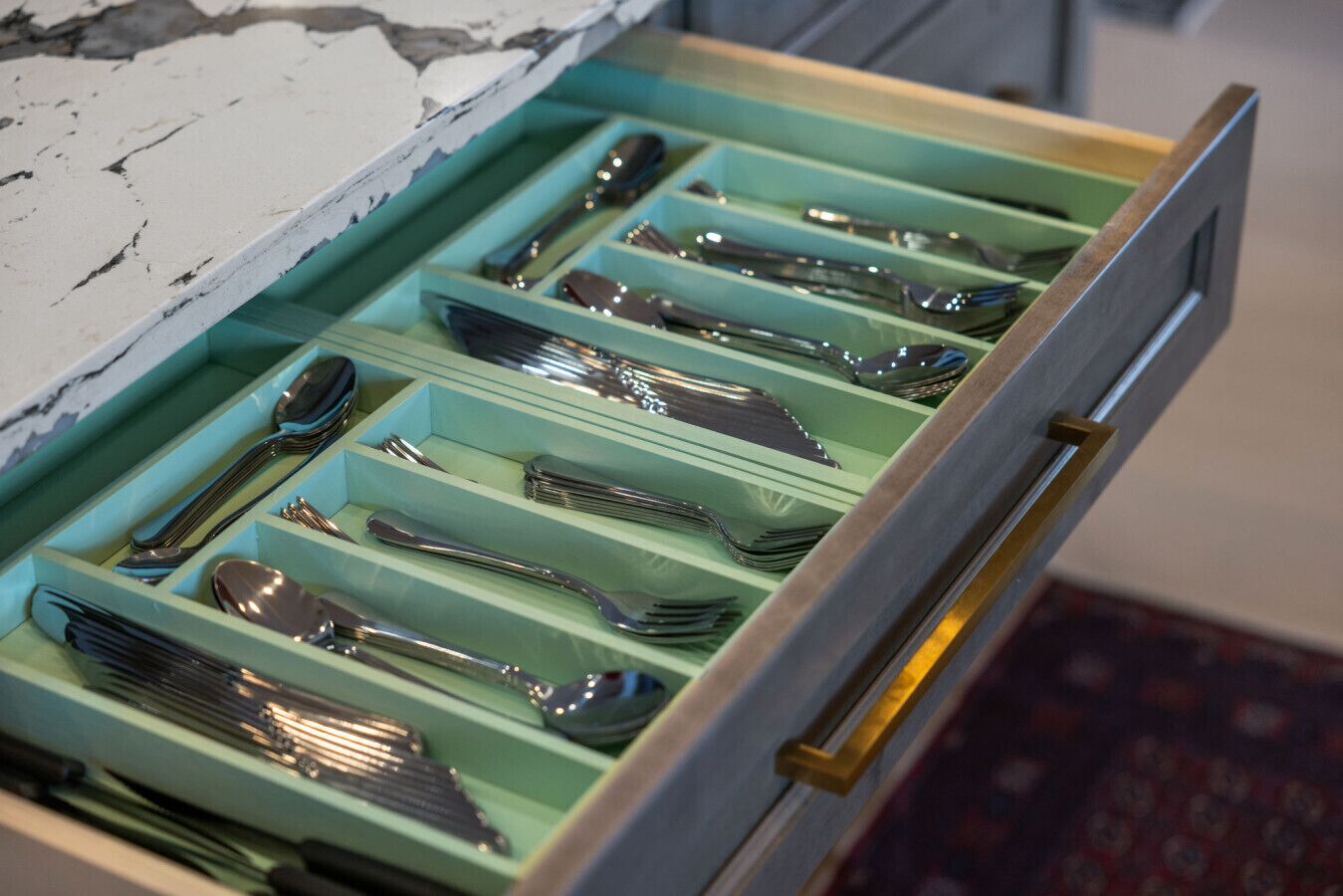 A drawer with multiple compartments containing various cutlery items.
