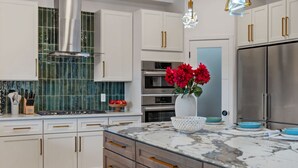 A modern kitchen with white cabinets, a stainless steel range hood, a Bosch oven, and a large refrigerator. - Mt. Washington Marvel. Stunning New Design, Epic Views, Hot Tub, Parking (Pittsburgh)