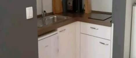 A compact kitchen with a sink, countertop, and cabinets.