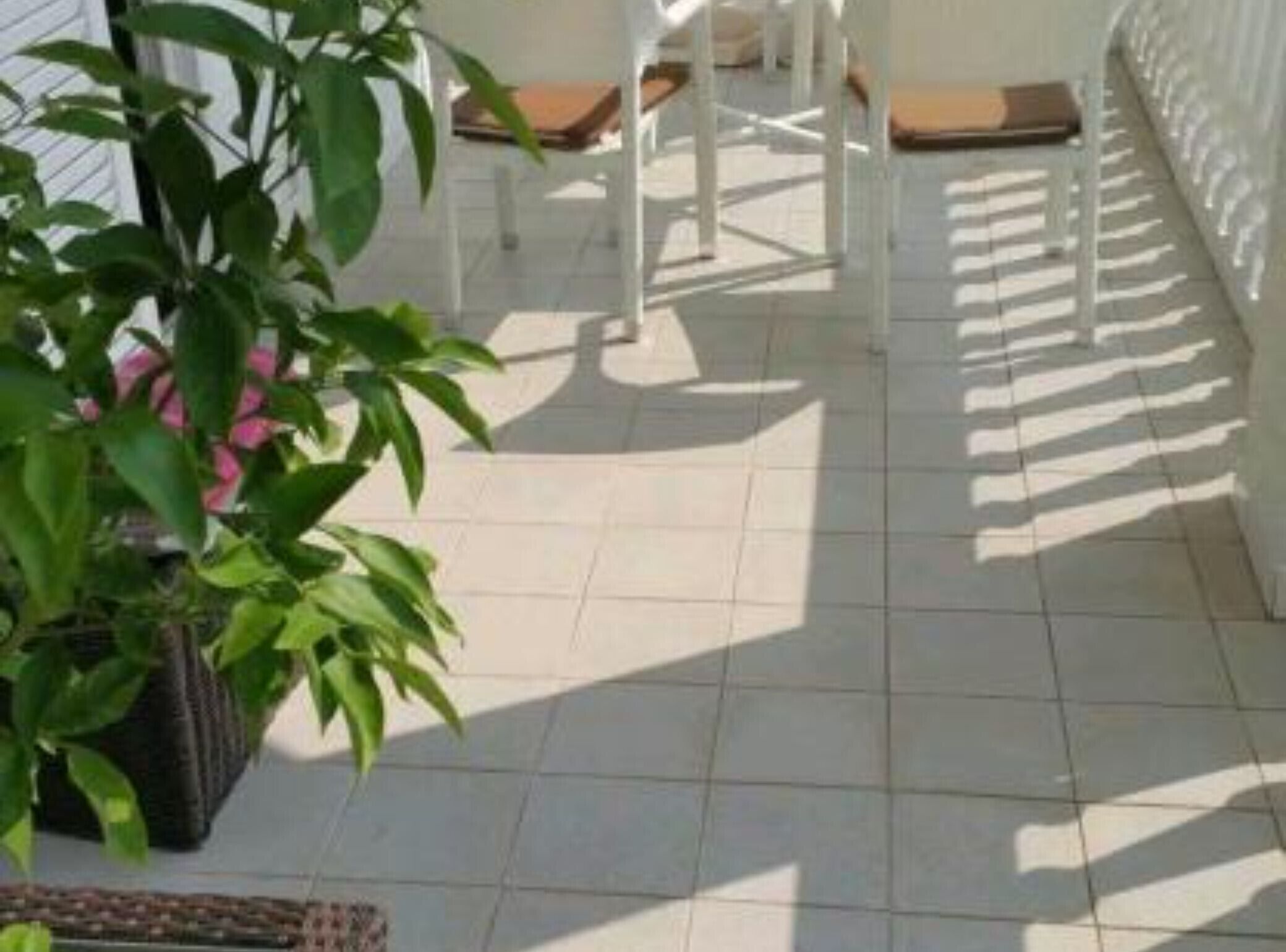 A tiled patio with a white chair and a potted plant.