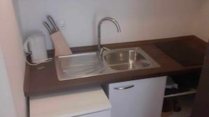 Een kleine keuken met een spoelbak, een koffiezetapparaat en een kleine koelkast.