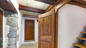 Ein Korridor mit Steinwand, Holztür und einer Treppe.