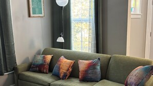 Un salon comprenant un canapé d’angle, une table basse, un lampadaire et un panneau décoratif accroché au mur.