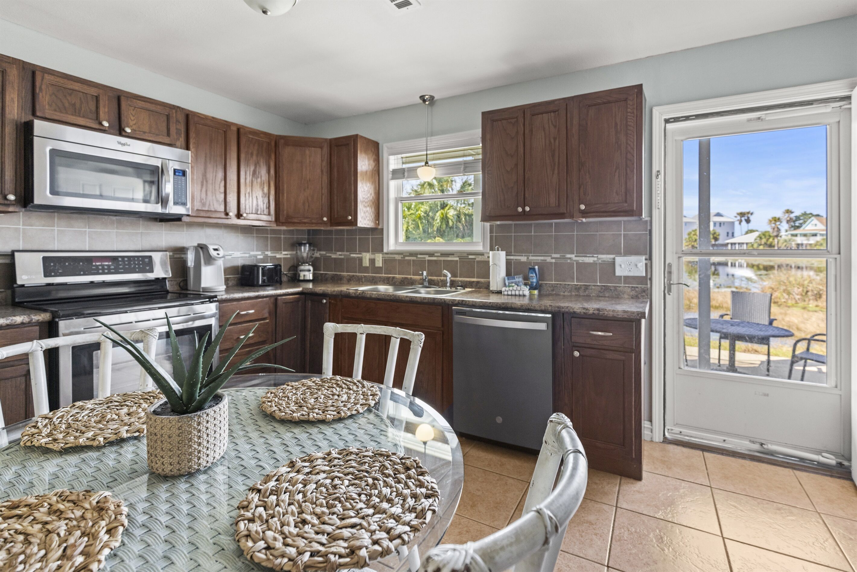 A kitchen with wooden cabinets, a microwave, a dishwasher, and a dining area with a table and chairs.