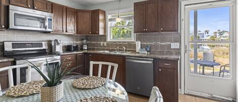 A kitchen with wooden cabinets, a microwave, a dishwasher, and a dining area with a table and chairs.
