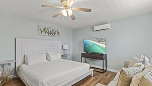 Une chambre avec un lit, un ventilateur de plafond, une télévision et une vue sur la plage.