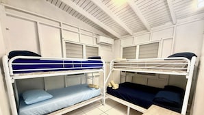 Een slaapzaal met stapelbedden, een klein houten bureau en een betegelde vloer.
