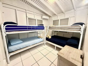 Ein Schlafsaalzimmer mit Etagenbetten, einem kleinen Holztisch und einem Fliesenboden.