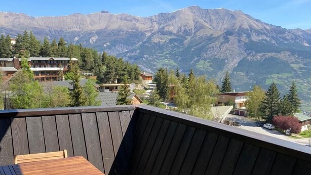 A balcony with a wooden table and chairs, a view of mountains, and a wooden railing. - 300m from ski slopes, 7th floor, balcony, tv, ski locker, 32m², Pra Loup (Pra Loup)