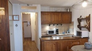 A kitchen with wooden cabinets, a microwave, and a sink. - 300m from ski slopes, 7th floor, balcony, tv, ski locker, 32m², Pra Loup (Pra Loup)