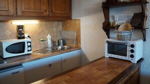 A kitchen with a microwave, toaster, sink, and wooden cabinets. - 300m from ski slopes, 7th floor, balcony, tv, ski locker, 32m², Pra Loup (Pra Loup)