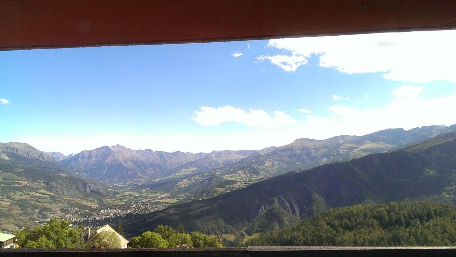A mountainous landscape with a valley, a small town, and a clear sky.