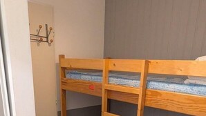 Una cama litera con escalera, una puerta con perchero y una pared gris.