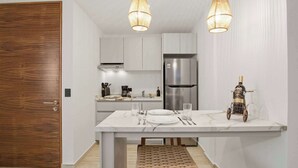 A modern kitchen with white cabinets, a stainless steel refrigerator, and a dining table set with plates and cutlery. - Rooftop Pool & Gym walkable studio full equipped (Playa del Carmen)