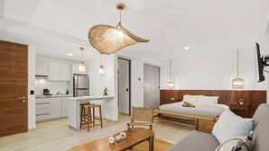 A modern hotel room with a kitchenette, a sofa, a dining table, and a large woven light fixture. - Rooftop Pool & Gym walkable studio full equipped (Playa del Carmen)