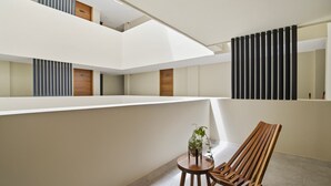 A modern interior with a wooden bench, a small table with a plant, and a view of a balcony with vertical blinds. - Rooftop Pool & Gym walkable studio full equipped (Playa del Carmen)