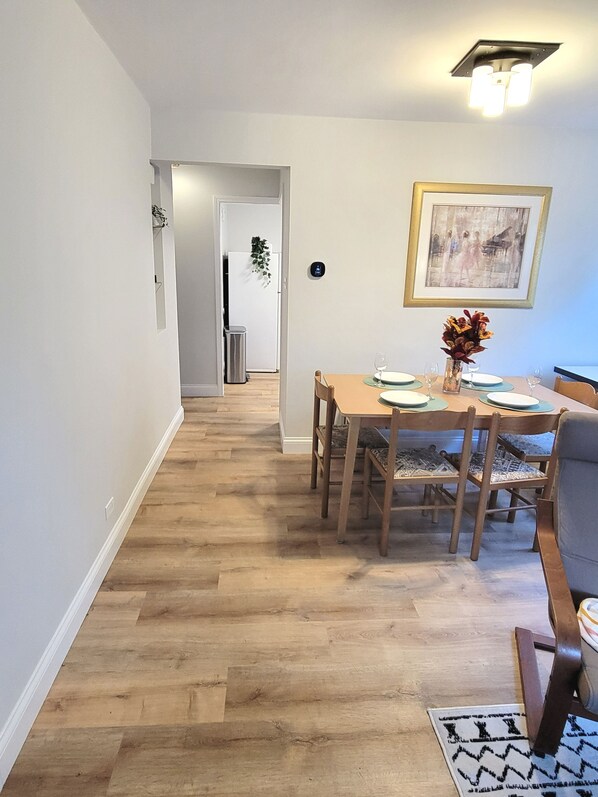 Un comedor con mesa de madera, sillas y un cuadro en la pared.