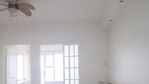 Amplia sala de estar con un sofá gris, una mesa de centro blanca y un ventilador de techo.
