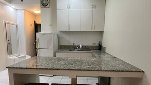 Una cocina con armarios blancos, encimera de granito y una banca empotrada.
