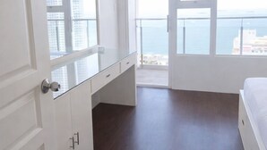 Un dormitorio con un ventanal grande, balcón y vista al mar.