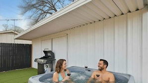 Ein Whirlpool für zwei Personen, ein Grill und ein umzäunter Garten.