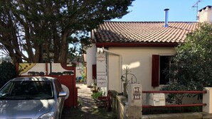 A residential building with a tiled roof, a car parked in front, and a gate with a number plaque. - Charming, super-central Landes house (Vieux-Boucau-les-Bains)