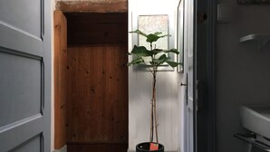 A hallway with a wooden door, a potted plant, and a white wall. - Charming, super-central Landes house (Vieux-Boucau-les-Bains)