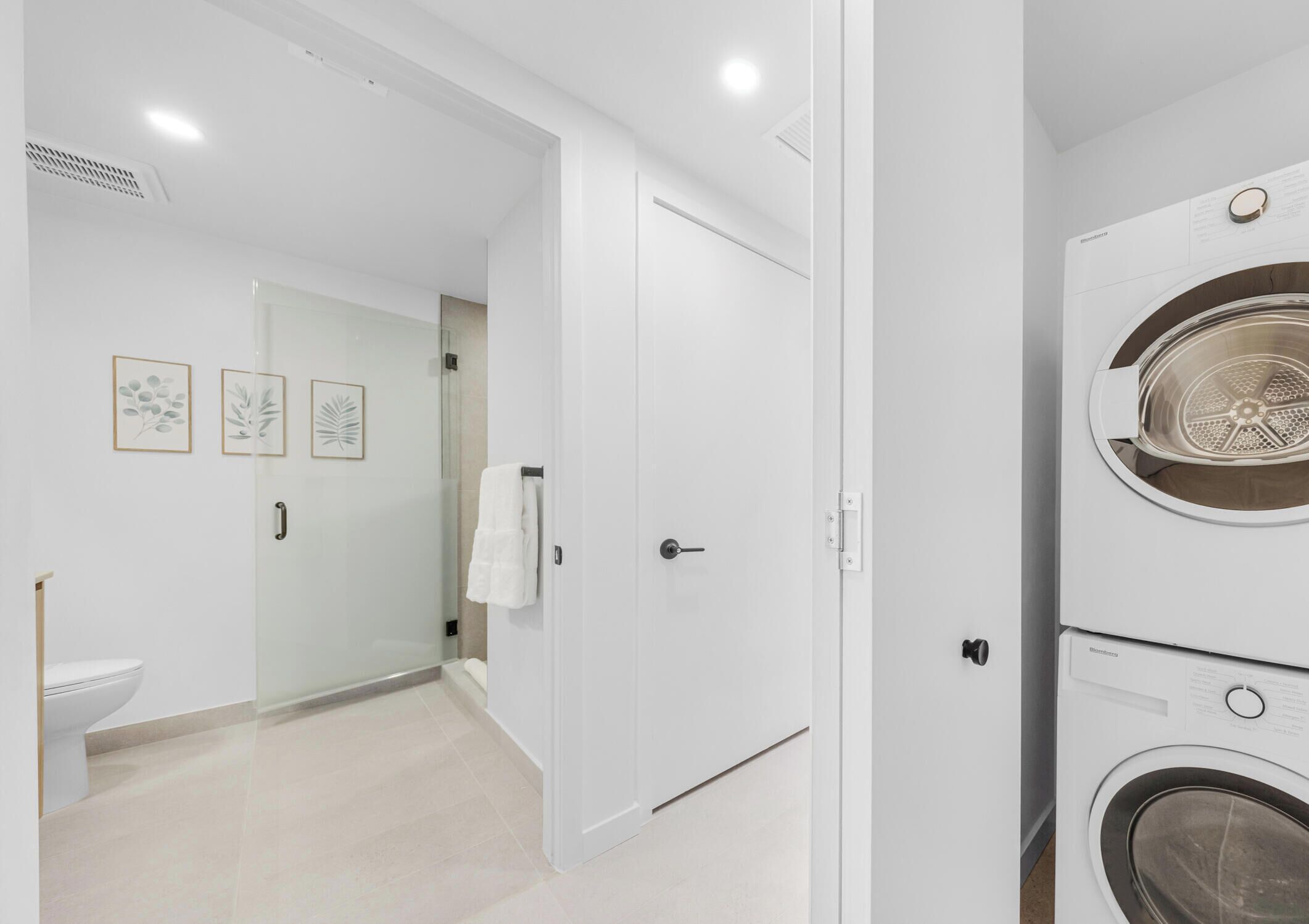 A modern bathroom with a toilet, a glass shower enclosure, and a white door.